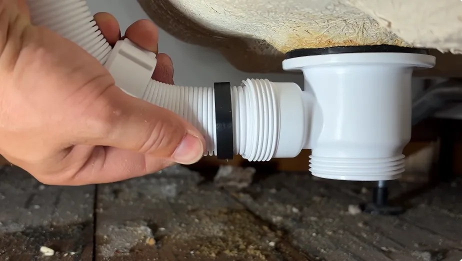 Plumber connecting a flexible waste pipe to a bathtub drain during a leak repair