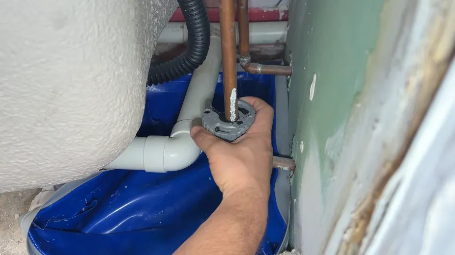 Plumber inspecting supply pipes and a valve behind a bathtub access panel